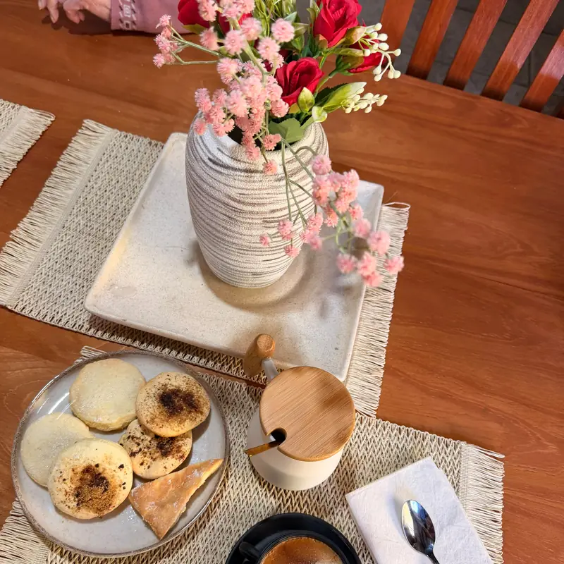 Desayuno servido en la mesa: tortitas caseras, café y un florero