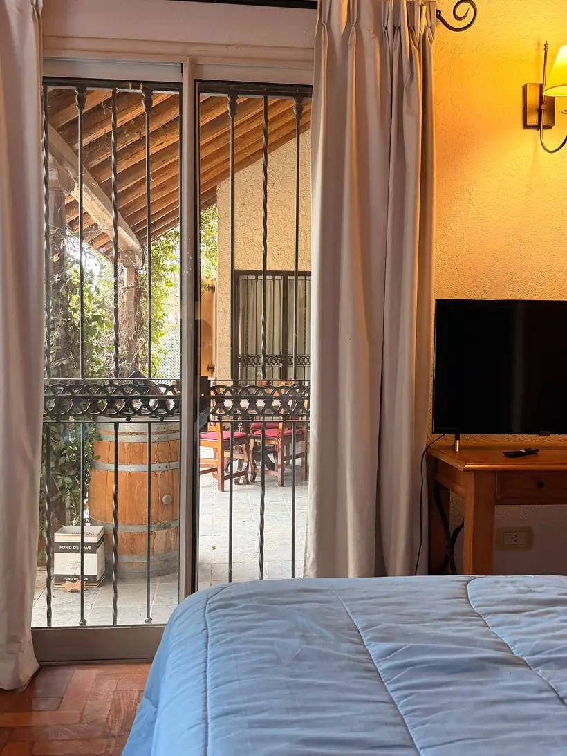 Habitación con puerta corrediza a la galería techada, con mesa y sillas afuera