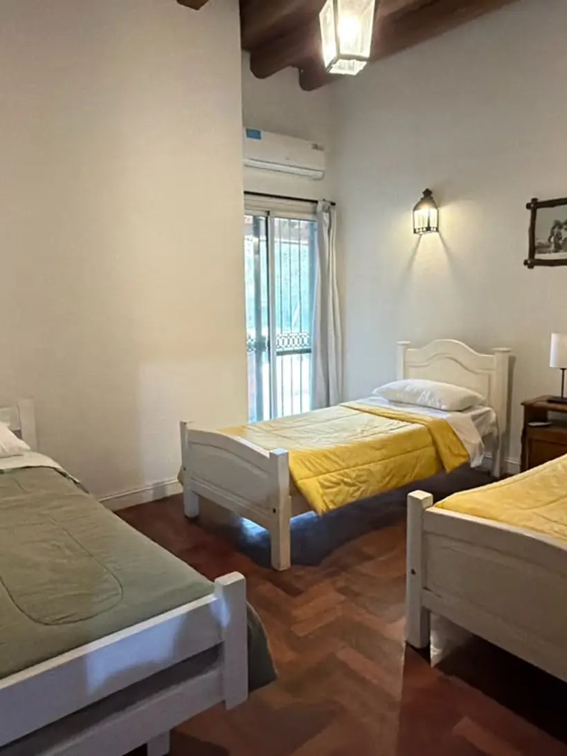 Habitación con tres camas individuales y piso de madera