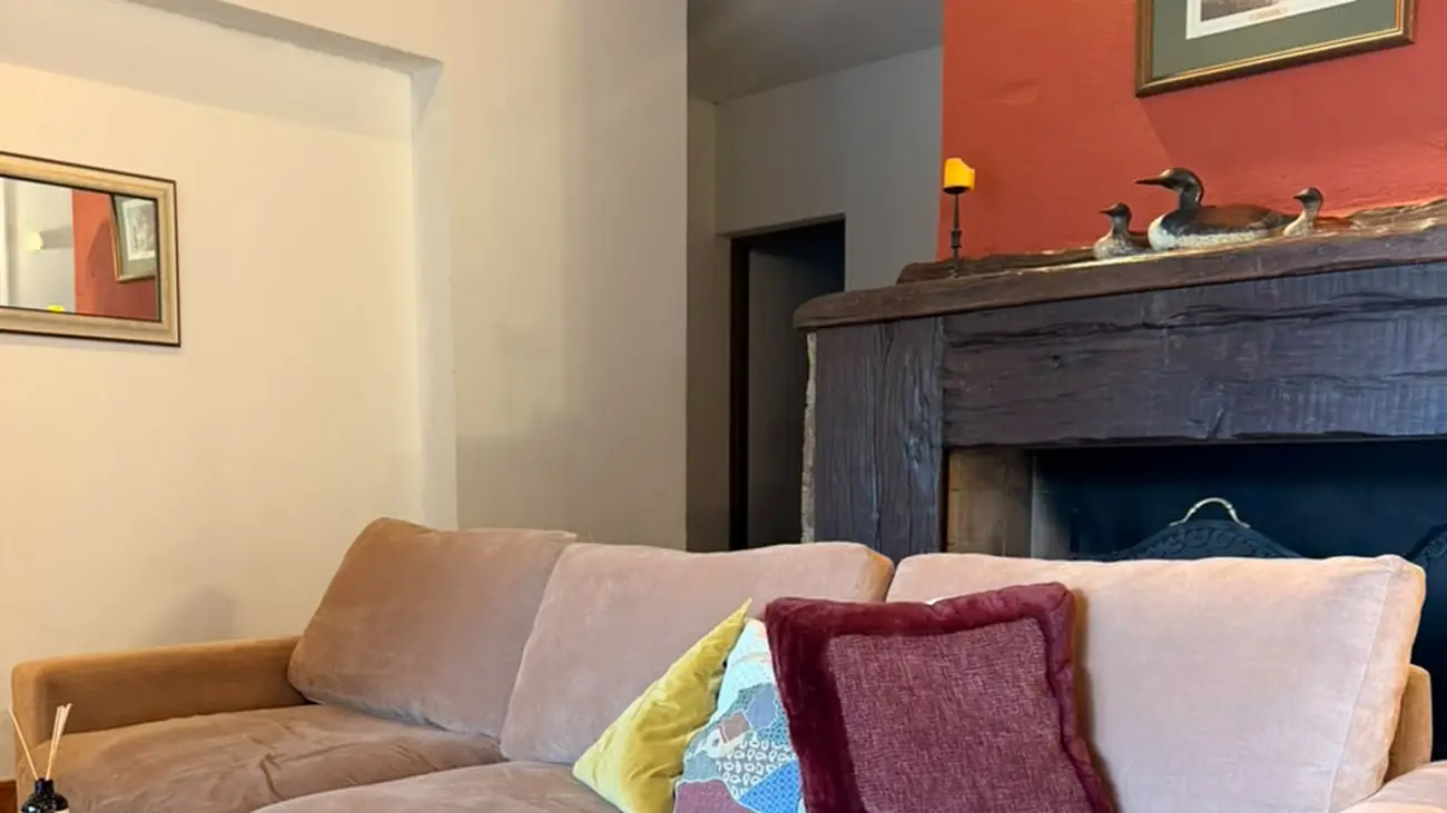 El living de la casa, con hogar a leña de marco de madera y sillón amplio